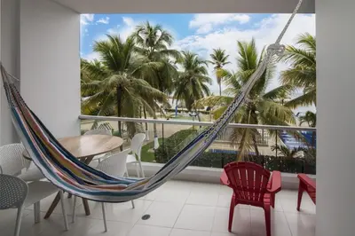 a hammock in a room with a balcony with palm trees at Magico Apartamento Frente al Mar 2 Habitaciones PAZ124 in Coveñas