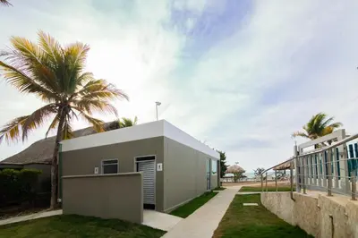 a house with a palm tree next to a building at Magico Apartamento Frente al Mar 2 Habitaciones PAZ124 in Coveñas