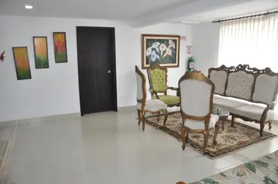 a living room with chairs and a door and paintings at Casa Hotel Manga Mar in Cartagena de Indias