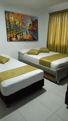 two beds in a room with a painting on the wall at Casa Hotel Manga Mar in Cartagena de Indias