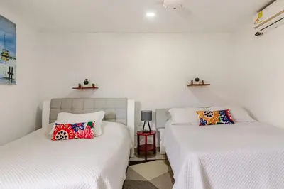 two beds in a room with white walls at Casa Rachel in Cartagena de Indias