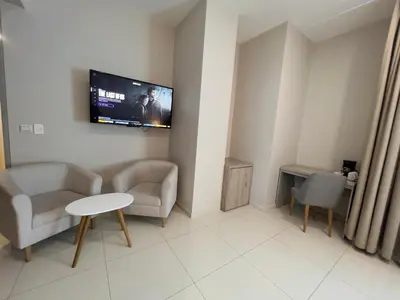 a living room with two chairs and a tv on the wall at Hotel Dorado Plaza Alto Prado in Barranquilla