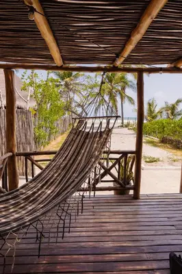 a hammock on a boardwalk with a beach at Paraíso Natural Ecohotel in San Bernardo del Viento