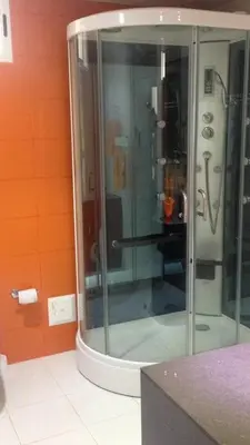 a glass shower in a bathroom with orange walls at APARTMENT WHITE BOCAGRANDE - Los Delfines in Cartagena de Indias
