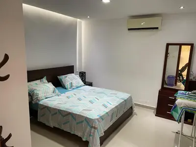 a bedroom with a bed and a mirror at APARTMENT WHITE BOCAGRANDE - Los Delfines in Cartagena de Indias