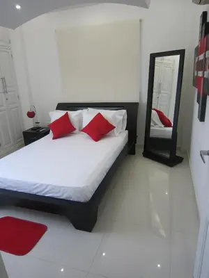 a bedroom with a bed with red pillows and a mirror at Hotel Valmar in Cartagena de Indias