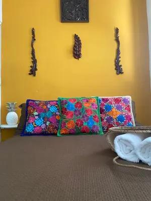 two colorful pillows on a bed with a yellow wall at Casa San Juan in Cartagena de Indias