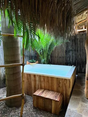 a hot tub in a straw hut with palm trees at Eco Xata in Santa Veronica