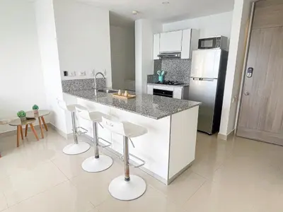 a kitchen with a counter with stools and a refrigerator at 22nd flr Spectacular Seaview Morros City Bocagrande in Cartagena de Indias