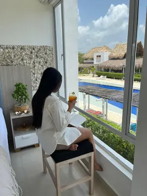 a woman sitting in a chair eating an apple by a window at Santo Manglar Cartagena Life Wellness Spa Hotel in Cartagena de Indias