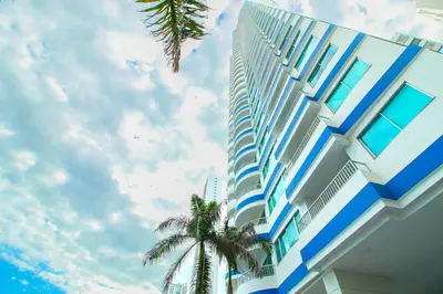 a blue and white building with a palm tree next to it at Apartamentos Palmetto - Frente al Mar in Cartagena de Indias