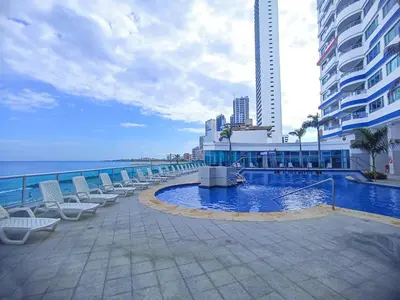 a resort swimming pool with chairs and the ocean at Apartamentos Palmetto - Frente al Mar in Cartagena de Indias