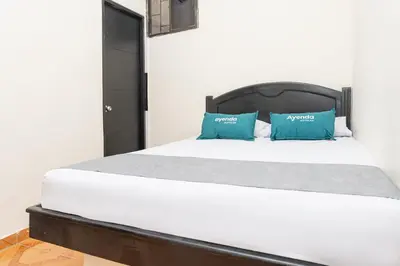 a bedroom with a white bed with blue pillows at Hotel Itaka in Soledad