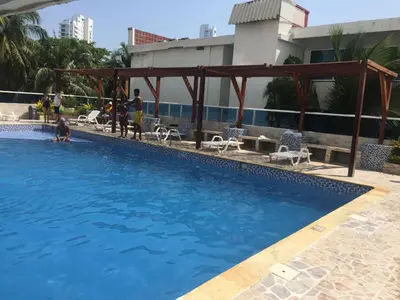 a swimming pool with chairs and people in a building at 1C5 APARTAMENTO EN CARTAGENA CON BALCON Y VISTA AL MAR, AIRE ACONDICIONADO Y WIFi in Cartagena de Indias