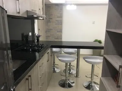 a kitchen with a black counter and stools in it at apartamento 807 moderno en el laguito, vista al mar in Cartagena de Indias