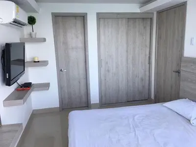 a bedroom with two doors and a tv and a bed at apartamento 807 moderno en el laguito, vista al mar in Cartagena de Indias