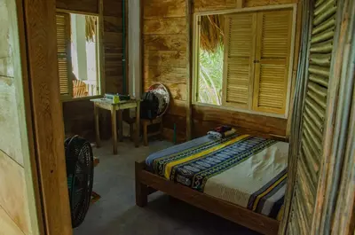 a bedroom with a bed and a table and windows at Rainbow Hostel in San Bernardo del Viento