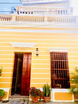 a yellow building with a red door and some plants at CASA PACHITA Getsemani in Cartagena de Indias