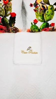 a white towel sitting on a bed with flowers at CASA PACHITA Getsemani in Cartagena de Indias