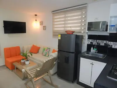 a living room with a couch and a black refrigerator at STUDIO DELFINES / BOCAGRANDE in Cartagena de Indias