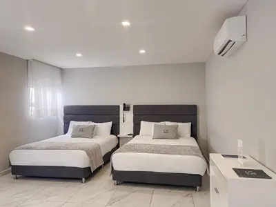 a bedroom with two beds and a tv on the wall at Hotel OR Suites in Barranquilla