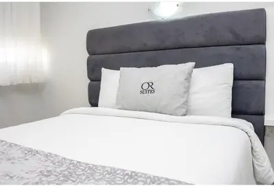 a white bed with a black headboard and white pillows at Hotel OR Suites in Barranquilla