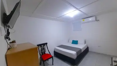 a bedroom with a bed and a desk and a television at Hotel Poblado Suite in Barranquilla