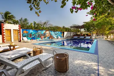 a swimming pool with white chairs and a mural at Marazao Beach Hotel & Spa in Tierra Bomba