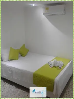 a white bed with a stuffed animal on a green blanket at HOTEL CASA GARCES in Cartagena de Indias