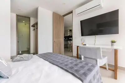 a bedroom with a bed and a desk and a television at Cómodo moderno apto en Bocagrande a 2' de la playa in Cartagena de Indias