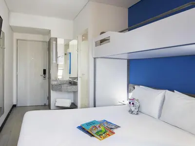 a bedroom with a white bed with a blue headboard at ibis budget Barranquilla in Barranquilla