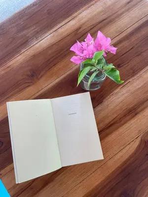 a book and a vase with pink flowers on a table at Hotel Las Casitas De Mar Adentro in Isla Grande