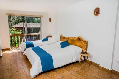 two beds in a room with a window at Hotel Restaurante Selva Negra in Turbaco
