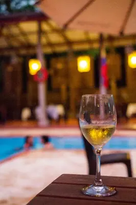a glass of wine sitting on a table next to a pool at Hotel Restaurante Selva Negra in Turbaco