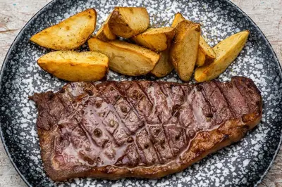 a plate with steak and potatoes on a table at Oz Hotel Luxury in Cartagena de Indias