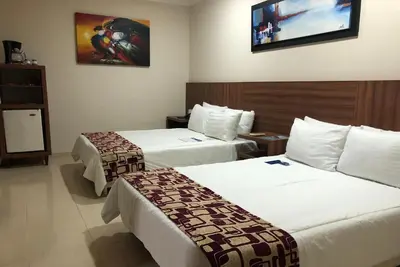 a hotel room with two beds and a tv on the wall at Howard Johnson by Wyndham Barranquilla Versalles in Barranquilla