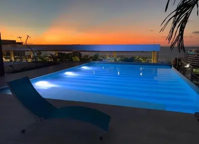 a large swimming pool with a sunset in the background at Martinique1621 in Cartagena de Indias