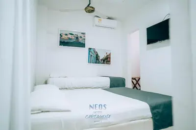two beds in a white room with a tv at Neos Hotel Cartagena in Cartagena de Indias