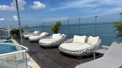 a row of lounge chairs sitting on a balcony overlooking the ocean at Spiaggia Morros Direct Beach Access in Cartagena de Indias