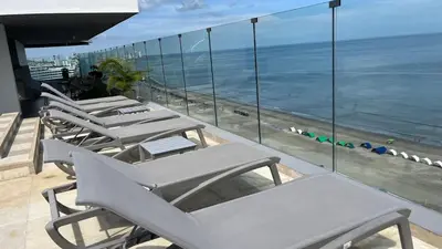 a row of lounge chairs on a balcony overlooking the beach at Spiaggia Morros Direct Beach Access in Cartagena de Indias