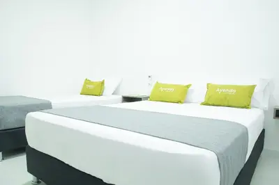 two beds in a room with white walls and yellow pillows at Hotel Ayenda House Concepción 1317 in Barranquilla