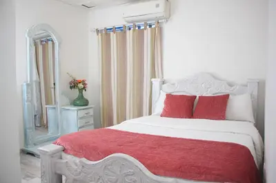 a bedroom with a white bed with red pillows and a mirror at Casa St James in Cartagena de Indias