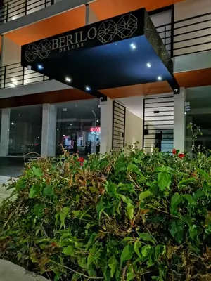 a bush in front of a building with a sign at Berilo Deluxe Apartahotel in Barranquilla