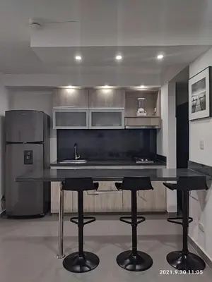 a kitchen with a black counter and bar stools at Berilo Deluxe Apartahotel in Barranquilla