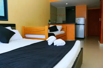 a bedroom with two beds and a kitchen with a refrigerator at Loft sea view 19C air and wifi in Cartagena de Indias