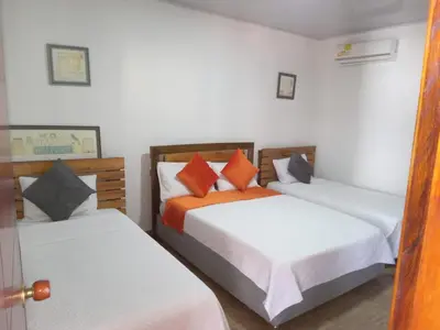 a bedroom with two beds with orange pillows at Hotel Campestre Maguey in Mangue