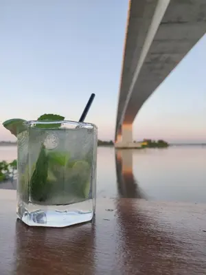 a drink in a glass sitting on a table next to a bridge at Hotel Campestre Maguey in Mangue