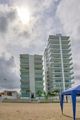 a large building on the beach next to a beach at Mágico Apartamento Frente al Mar 3 Habitaciones PV21 in Coveñitas