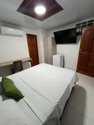 a bedroom with a large white bed and a television at Villa Santos Apartaestudios in Barranquilla
