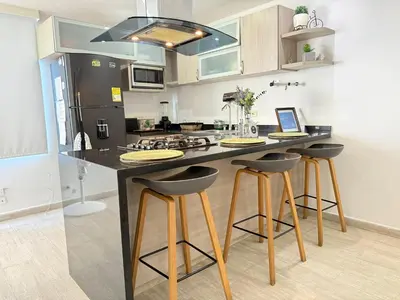 a kitchen with a black counter top and stools at A un Paso de la Playa in Cartagena de Indias